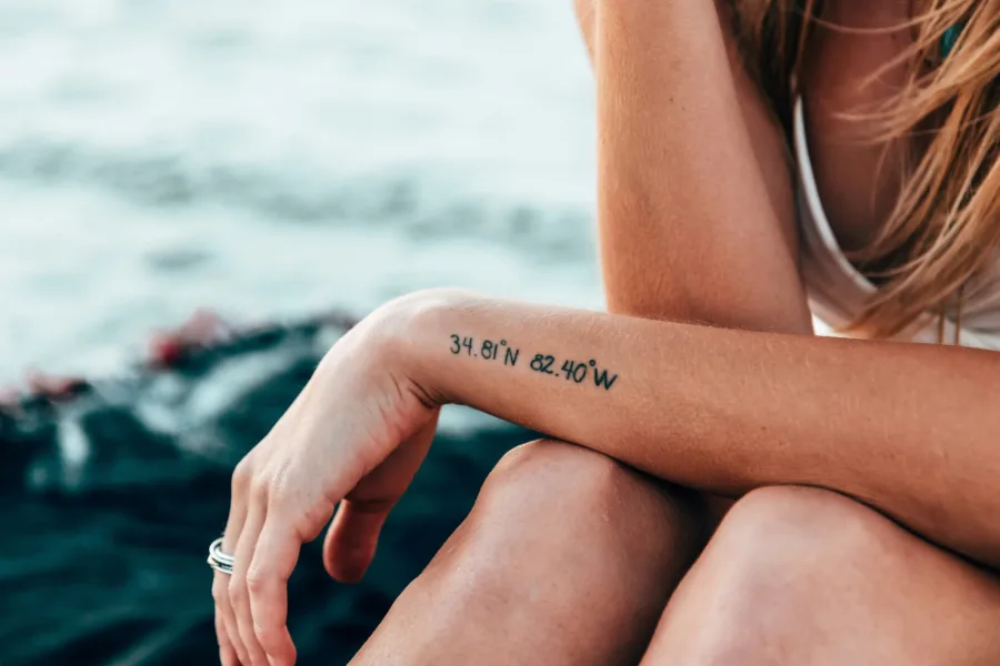 Γυναίκα με tattoo συντεταγμένων στο χέρι, ιδανικό για το πρώτο σου tattoo, δίνοντας έμπνευση για την επιλογή του.