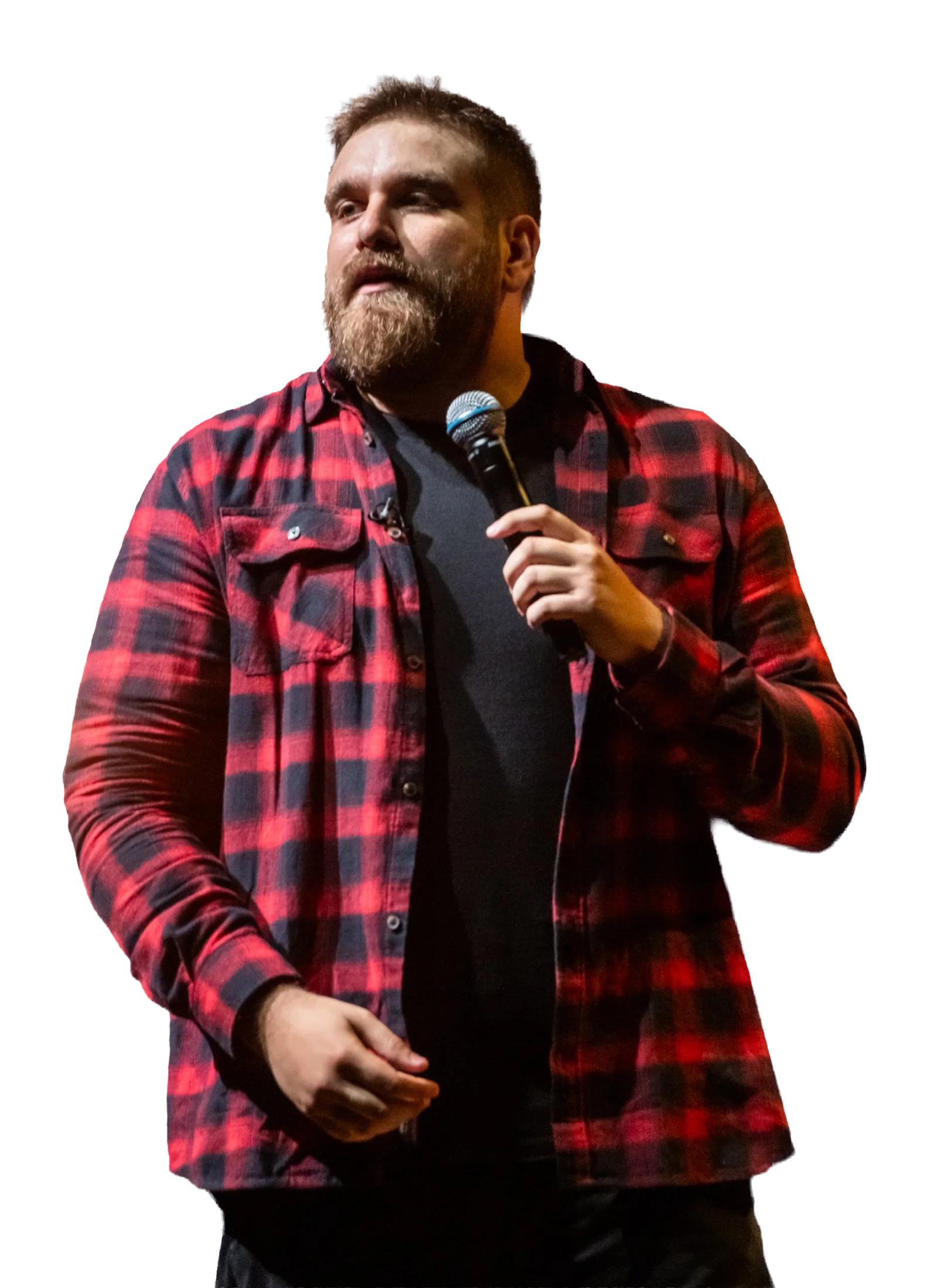 Άνδρας stand-up κωμικός με μούσι και καρό πουκάμισο μιλάει σε μικρόφωνο