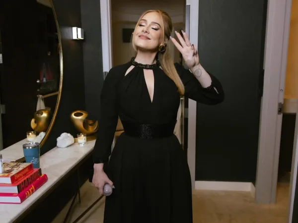 Η Adele με κομψό μαύρο φόρεμα κάνει σήμα με το χέρι, αποθεώνοντας τον Bad Bunny.