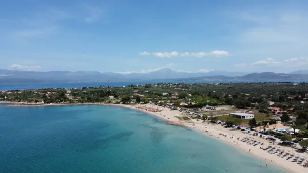 Παραλία με γαλαζοπράσινα νερά και ορεινό τοπίο στο βάθος, ιδανική για μονοήμερη εκδρομή κοντά στην Αθήνα.
