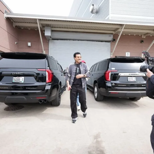 Ο Lionel Richie περπατάει ανάμεσα σε δύο μαύρα SUV έξω από κτίριο στη Minnesota, μετά από αδιαθεσία στη σκηνή.