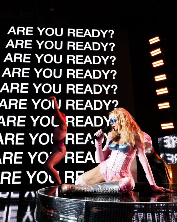 Η Madonna σε secret show στην Times Square, με φόντο την ερώτηση "ARE YOU READY;" και χορευτές.
