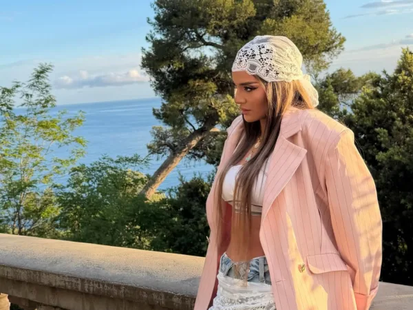 Η Ρία Ελληνίδου με ροζ σακάκι και μαντήλα ποζάρει με φόντο τη θάλασσα στη Γαλλία.