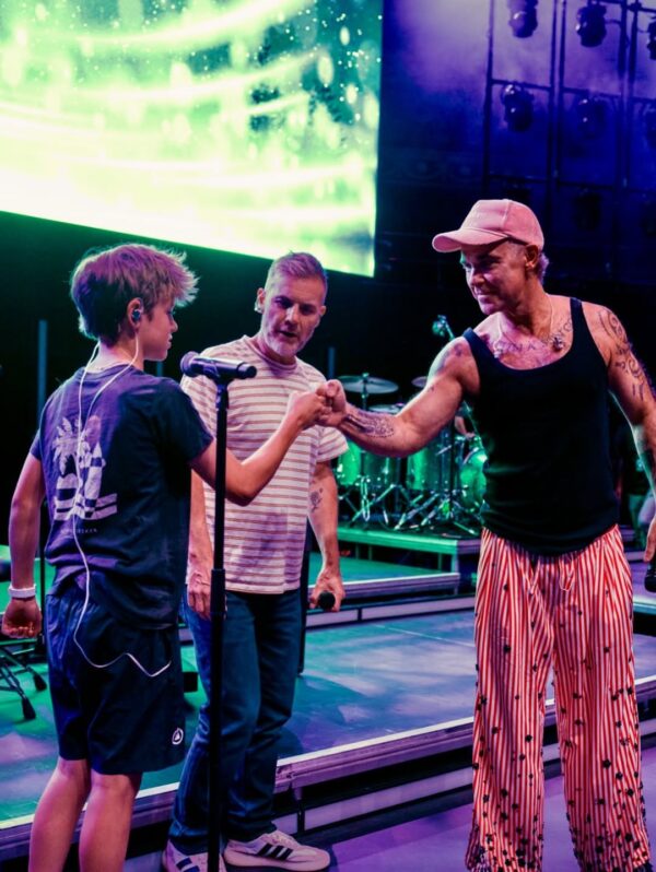 Robbie Williams και Gary Barlow κάνουν χειραψία με τον γιο του Robbie, Beau, κατά την επανένωσή τους στη σκηνή μετά από μια δεκαετία.