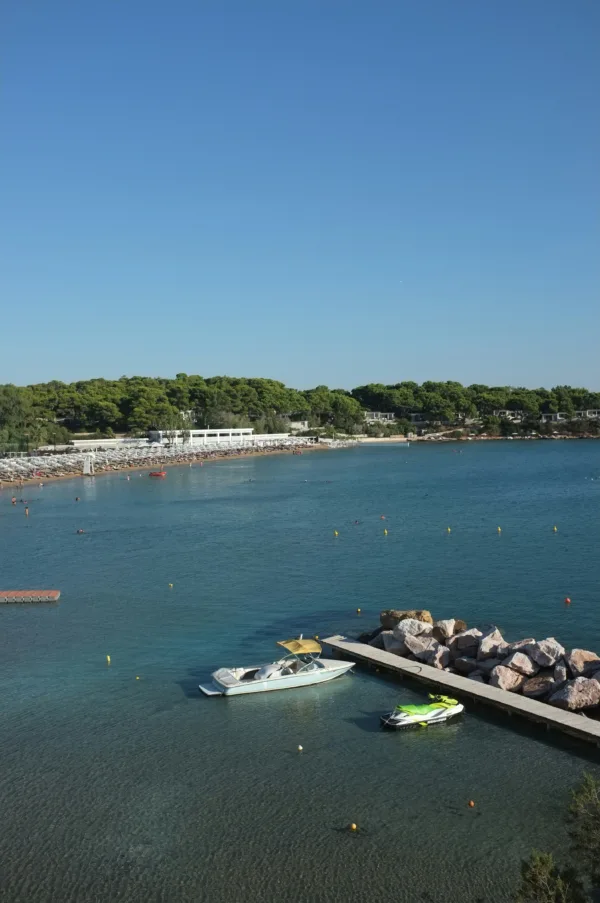 Παραλία στην Αθήνα με ξαπλώστρες, σκάφη και νησιώτικα vibes, ιδανική για διακοπές.