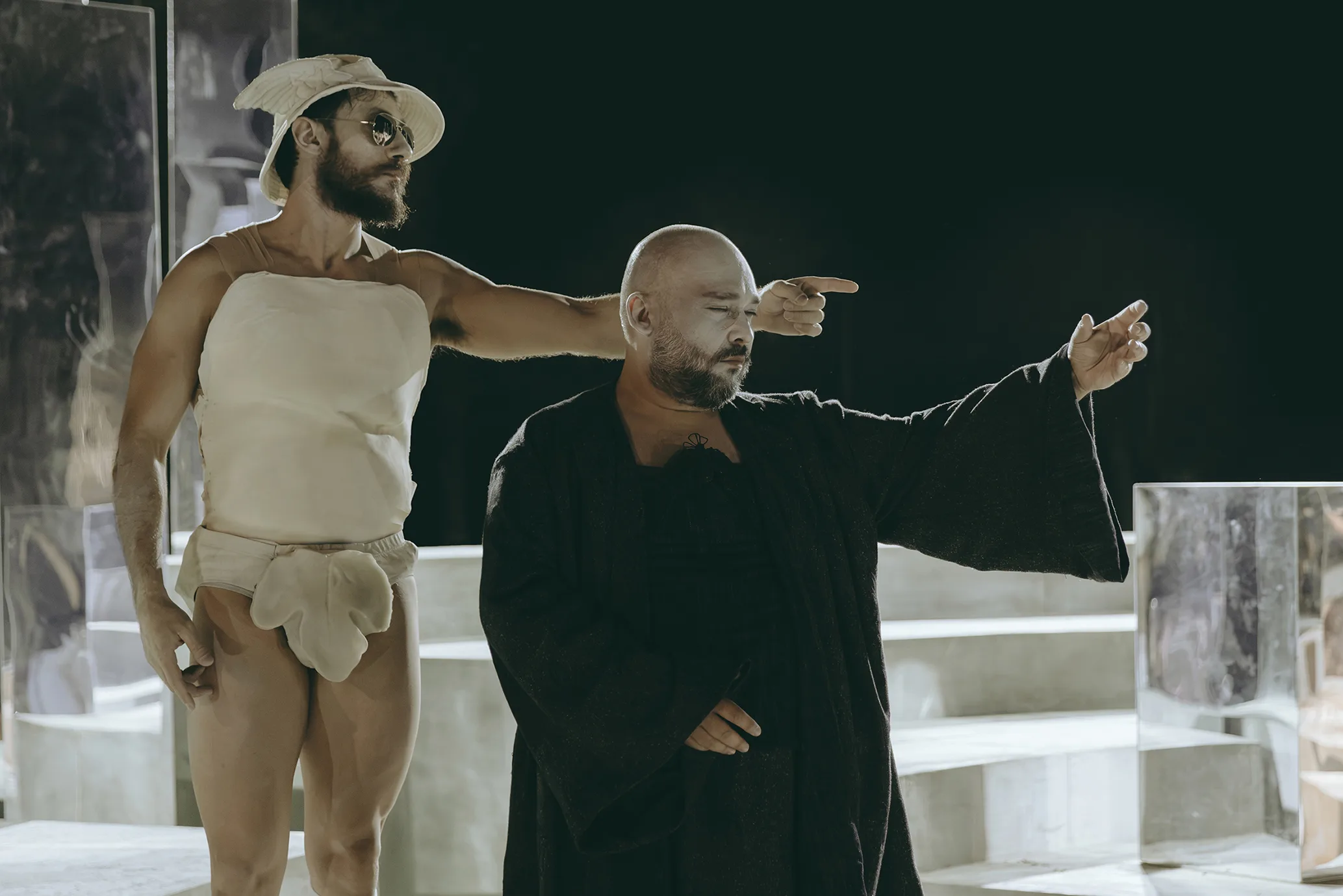 Η παράσταση «Ίωνας» του Θοκ στην Επίδαυρο με σκηνοθεσία Θωμά Μοσχόπουλου παρουσιάζει δύο άνδρες σε σκηνικά αντικείμενα.