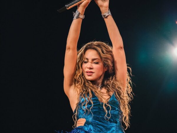 Η Shakira στη σκηνή με μπλε ρούχο κρατώντας μικρόφωνο ψηλά