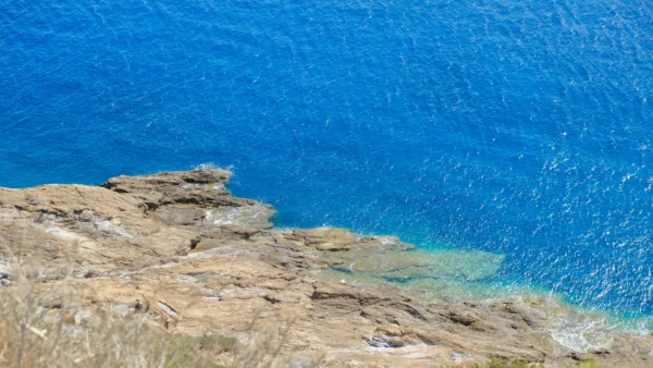 Βραχώδης ακτογραμμή με γαλάζια νερά, μια από τις instagrammable παραλίες κοντά στην Αθήνα, ιδανική για φωτογραφίες.