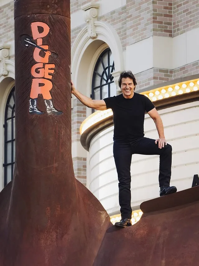 Ο Tom Cruise χαμογελάει ποζάροντας πάνω σε μεταλλική κατασκευή με την επιγραφή Digger.