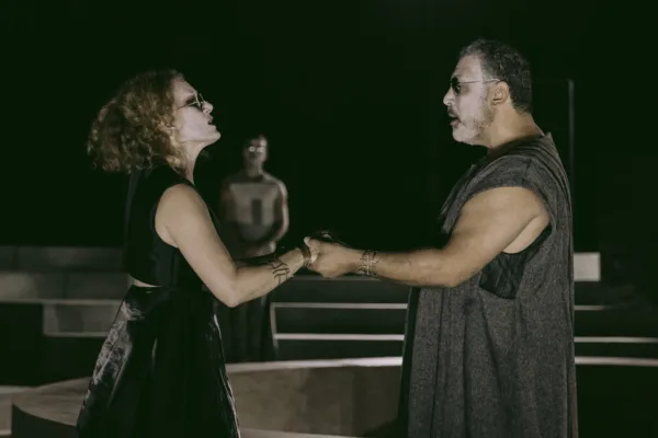 Η παράσταση «Ίων» στο Φεστιβάλ Επιδαύρου με ηθοποιούς να κρατούν ο ένας το χέρι του άλλου σε σκηνή.