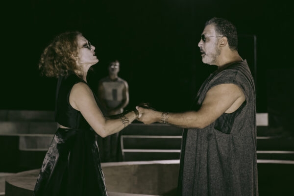 Η παράσταση «Ίων» στο Φεστιβάλ Επιδαύρου με ηθοποιούς να κρατούν ο ένας το χέρι του άλλου σε σκηνή.