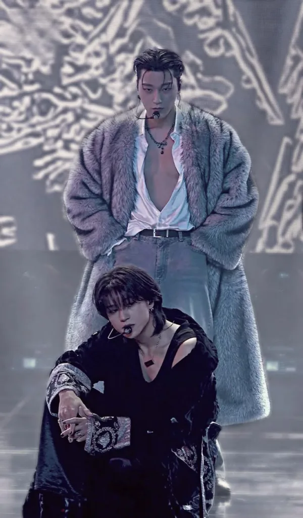 Δύο καλλιτέχνες K-pop με εντυπωσιακά κοστούμια επί σκηνής, παρουσιάζοντας τους όρους της μουσικής σκηνής.