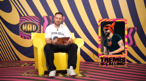 Ο Akylas δεξιά, μιλάει για την Eurovision στο «OK! Themis» με φόντο το MAD TV.