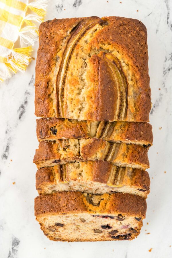 Ένα υγιεινό banana bread κομμένο σε φέτες, με μπανάνα στην επιφάνεια, έτοιμο για απόλαυση.