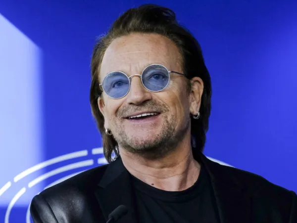Ο Bono των U2 με γυαλιά ηλίου και μπλε φόντο, σε μια σκηνή που συνδέεται με το νέο άλμπουμ τους.