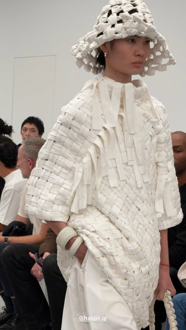 Μοντέλο παρουσιάζει τη νέα συλλογή Bottega Veneta SS27 με εντυπωσιακό λευκό σύνολο και καπέλο, αναδεικνύοντας την κίνηση.