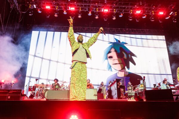 Σκηνική εμφάνιση του συγκροτήματος Gorillaz με τον 2D να εμφανίζεται στην οθόνη, στο πλαίσιο των 25 χρόνων του συγκροτήματος.