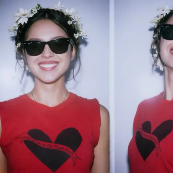 Η Olivia Rodrigo με στεφάνι λουλουδιών και γυαλιά ηλίου φοράει κόκκινο μπλουζάκι με καρδιά και σαρώνει στα charts.