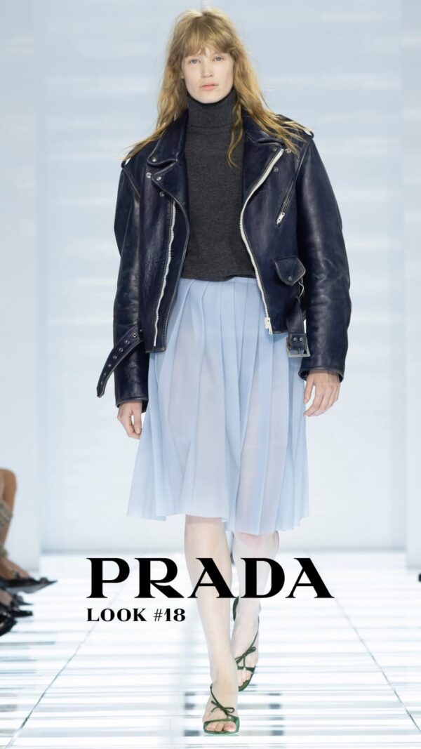 Μοντέλο παρουσιάζει δημιουργία του οίκου Prada με δερμάτινο τζάκετ και αέρινη φούστα, επαναπροσδιορίζοντας τη θηλυκότητα.