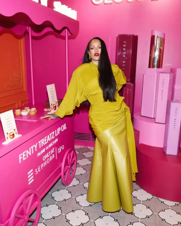Η Rihanna ποζάρει δίπλα σε ένα ροζ καρότσι Fenty Beauty, προωθώντας τα νέα προϊόντα της.