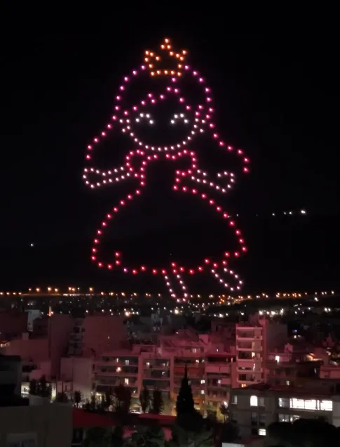 Εντυπωσιακό drone show με ζωγραφιές παιδιών να σχηματίζουν μια φιγούρα κοριτσιού στον νυχτερινό ουρανό πάνω από την πόλη.
