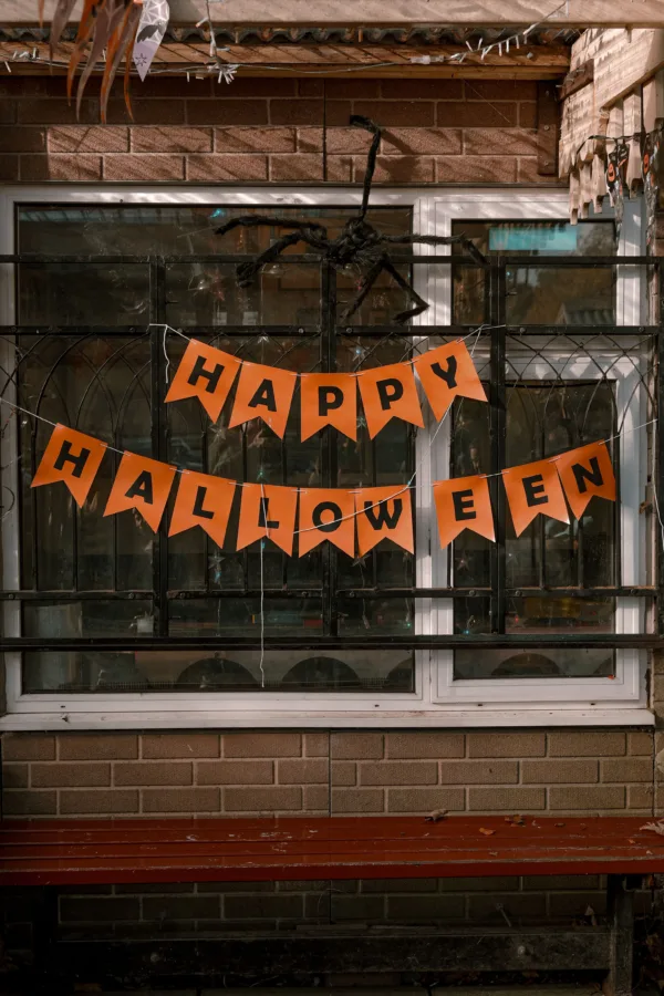 Διακόσμηση για το Halloween με πορτοκαλί γιρλάντα και αράχνη πάνω από παράθυρο, ιδέες για το σπίτι.