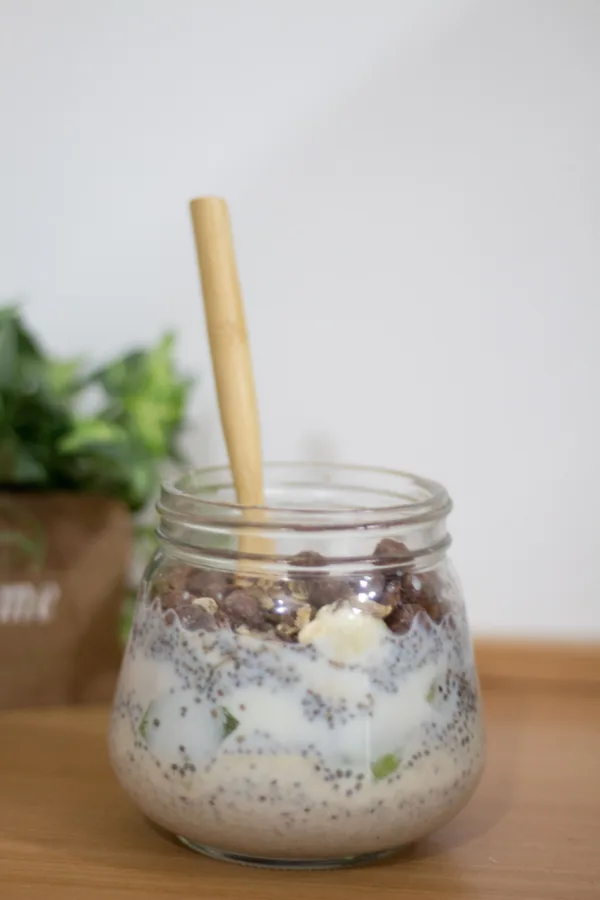 Ένα γυάλινο βάζο με overnight oats, φρούτα, δημητριακά και μπανανά, έτοιμο για κατανάλωση ως ένα υγιεινό πρωινό.