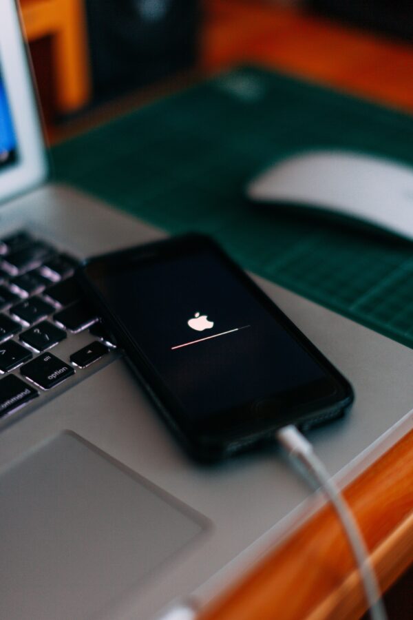 Ένα iPhone φορτίζει πάνω σε ένα laptop, με την ένδειξη φόρτισης να είναι ορατή, σχετικό με το λάθος που καταστρέφει την μπαταρία.