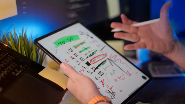 Χέρι κρατάει tablet με λίστα "to do" και στυλό, απεικονίζοντας την παγίδα του hustle culture.