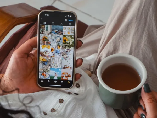 Χέρι κρατάει smartphone με ατελείωτο scrolling σε Instagram feed, δίπλα σε φλιτζάνι τσάι, δείχνοντας το viral wellness trend.