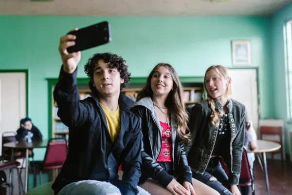 Τρεις έφηβοι τραβούν selfie με κινητό τηλέφωνο, δείχνοντας πώς οι νέοι βρίσκουν τρόπους να ξεγελούν τις απαγορεύσεις στα social media.